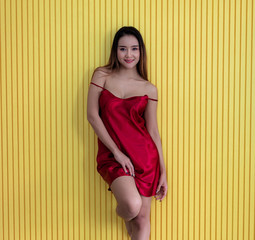 Asian girl is wearing red dress. Standing sexy pose. With  yellow background. Colorful fashion Beautiful girl with happy expression. The red dress and the yellow background make the model stand out.