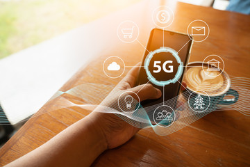Close up of female hand holding a phone with a 5G hologram in coffee shop. 5G network wireless...