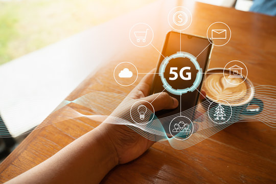 Close up of female hand holding a phone with a 5G hologram in coffee shop. 5G network wireless systems.The concept of 5G network, high-speed mobile Internet, new generation networks.
