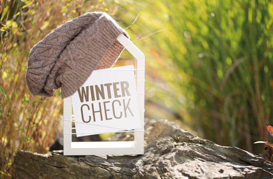 Wei&szlig;es Haus im Garten mit Schild Wintercheck