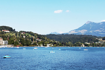 Boats in harbor in Lucerne Switzerland city with mountain rigi in background blue sky and water