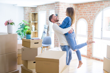 Fototapeta na wymiar Young beautiful couple hugging at new home around cardboard boxes