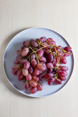 pink grapes in a gray plate on a light background