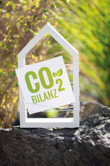 Weißes Haus im Garten mit Schild CO2 Bilanz