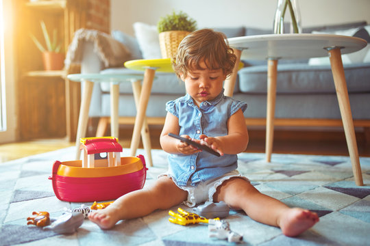 Beautiful toddler child girl sitting on the carpet playing with smartphone