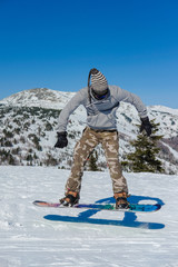 Young snowboarder riding in the mountains on a snowboard.
