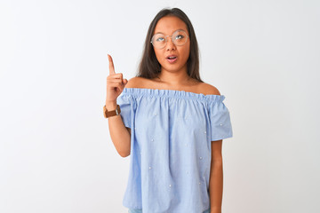 Fototapeta premium Young chinese woman wearing blue t-shirt and glasses over isolated white background pointing finger up with successful idea. Exited and happy. Number one.