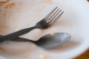 Dirty plate with spoon and fork after a meal