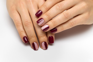 Hands close up. Burgundy beige manicure with a pink shiny strip on short square nails. Half a manicure. Color manicure.