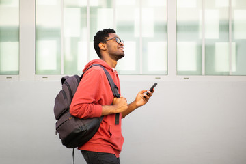 african american college student walking with mobile phone and bag