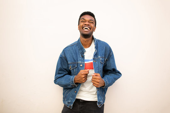happy african american young man laughing and looking up by white background