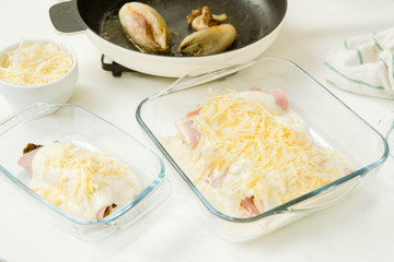 Braised chicory rolled in ham and cheese bechamel in  glass oven dishes ready for gratin