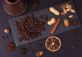 Beautiful composition of coffee beans, utensils for making coffee and decor in the form of almonds, dried slices of lemon, peanut and cinnamon on black and blue backgrounds.