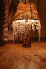 a lamp with a lampshade stands on a wooden surface casts bizarre shadows and illuminates the whole space with a warm golden light