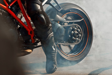 The smoke comes out from under the wheels. Motorcycle wheel closeup. Smoke due to tire rubbing...