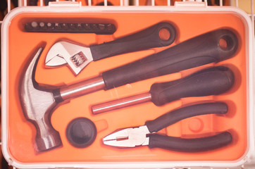 Orange box, set with the necessary tools for repair, fixing: hammer, pliers, screwdriver, wrench, screwdriver.