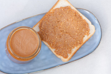 Creamy peanut butter in jar and sandwich.