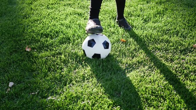 An athletic soccer player dribbling a football up the field to score a goal to win the sports game SLOW MOTION.