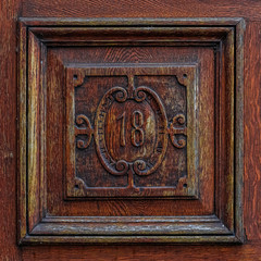 Old wood carving with the number 18. Vintage, weathered wooden tile saying eighteen. Vintage carpenter design. Text, script concept