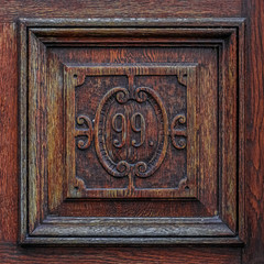 Old wood carving with the number 99. Vintage, weathered wooden tile saying ninety-nine. Vintage carpenter design. Text, script concept