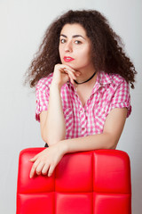 A girl  leans on a red chair. Portrait.