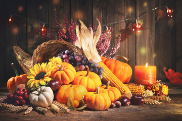 Pumpkins with fruits and falling leaves on rustic wooden table