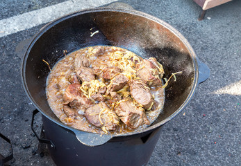 Pieces of meat cooking in a large cauldron