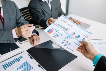 Business people pointing their hands at the data graph to analyze and plan their financial and investment strategy at meeting.