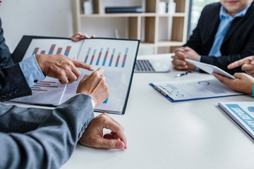 Business people pointing their hands at the data graph to analyze and plan their financial and investment strategy at meeting.