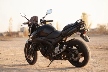 Cercles muraux Moto Une moto noire dans le désert.
