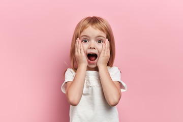 Close up photo little beautiful emotioal excited girl touching her cheeks, close up portrait,...