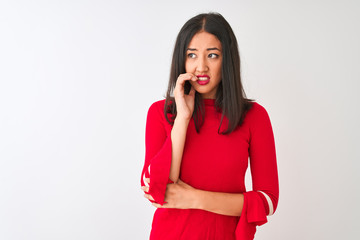 Young beautiful chinese woman wearing red dress standing over isolated white background looking stressed and nervous with hands on mouth biting nails. Anxiety problem.