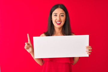 Naklejka premium Young beautiful chinese woman holding banner standing over isolated red background surprised with an idea or question pointing finger with happy face, number one
