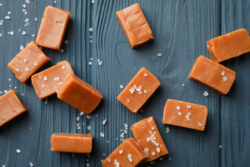 Salted caramel candies on wooden background, top view