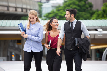 group of three young multi ethnic business people walking outside office talking with colleagues in urban city outdoors. happy African American woman employee  smiling with manager. teamwork.