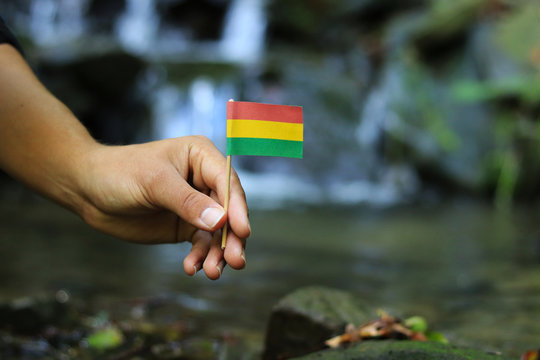 Poor Bolivia in the hands of powerful people. Young man holds flag of Bolivia near stream. Concept of humanity and dominance. Prove of depraved and avariciousness. Problems with drogs