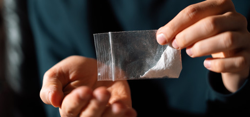 drug addict hands holding a small package with white powder