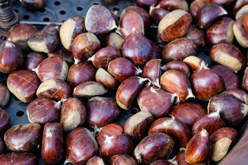Fall and winter rustic dessert sweet roasted chestnuts in a large metallic bowl, available for sale at a street food market festival, seasonal food photograph with selective focus