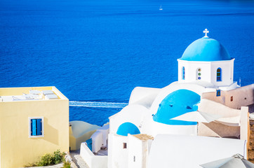 Traditional white architecture and greek orthodox churches with blue domes over the Caldera in Aegean