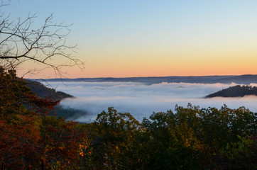 Fototapeta na wymiar Early morning fog blankets the valley below. On a sunrise fall morning.