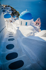 Traditional white architecture and greek orthodox churches with blue domes over the Caldera in...
