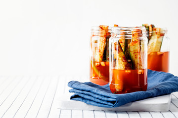 Vegan Korean Kimchi pickle cucumber.Homemade crisp,crunchy fermented marinated cucumbers in jar on white background with copy space.The concept of winter canned food. A simple recipe of fermentation
