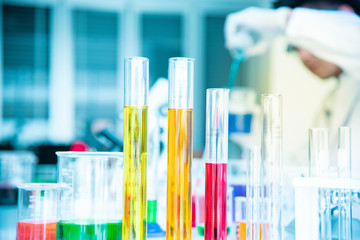 Several test tubes and solution beakers in a science laboratory with liquid of different colors on...