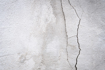 Gray concrete wall texture painted with white There are cracks from the top to the bottom of the image. With old white color that has been fading and peeling off