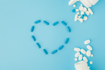 Pharmaceutical medicine pills, tablets and capsules in the shape of a heart on a blue background