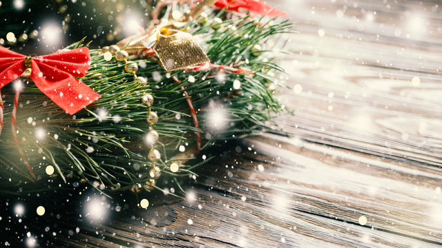 New Year and Christmas concept. A fragment of a Christmas wreath with a red bow and falling fluffy snow. Copy space for text