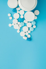 Assorted pharmaceutical medicine pills, tablets and capsules and bottle on blue background. Copy space for text
