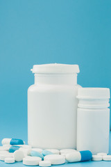 Assorted pharmaceutical medicine pills, tablets and capsules and bottle on blue background. Copy space for text