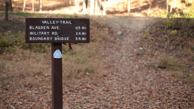 Sign for Valley Trail, Runners pass by  - Rock Creek Park - Washington, DC - Autumn