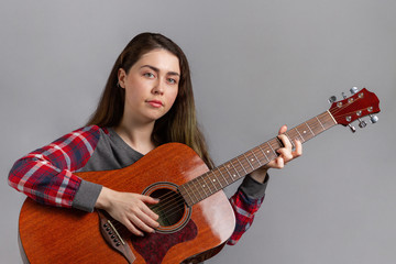 Portrait of a young pretty woman with an acoustic guitar in her hands. Close up